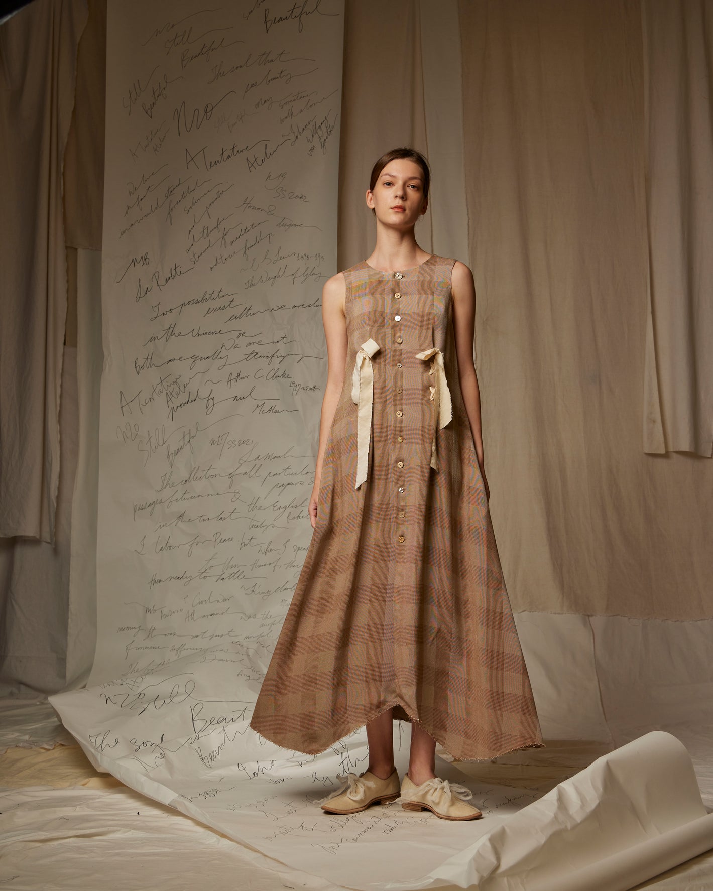 A Tentative Atelier SS23 Lookbook Womens sleeveless brown check dress with buttons and ribbon tie detailing