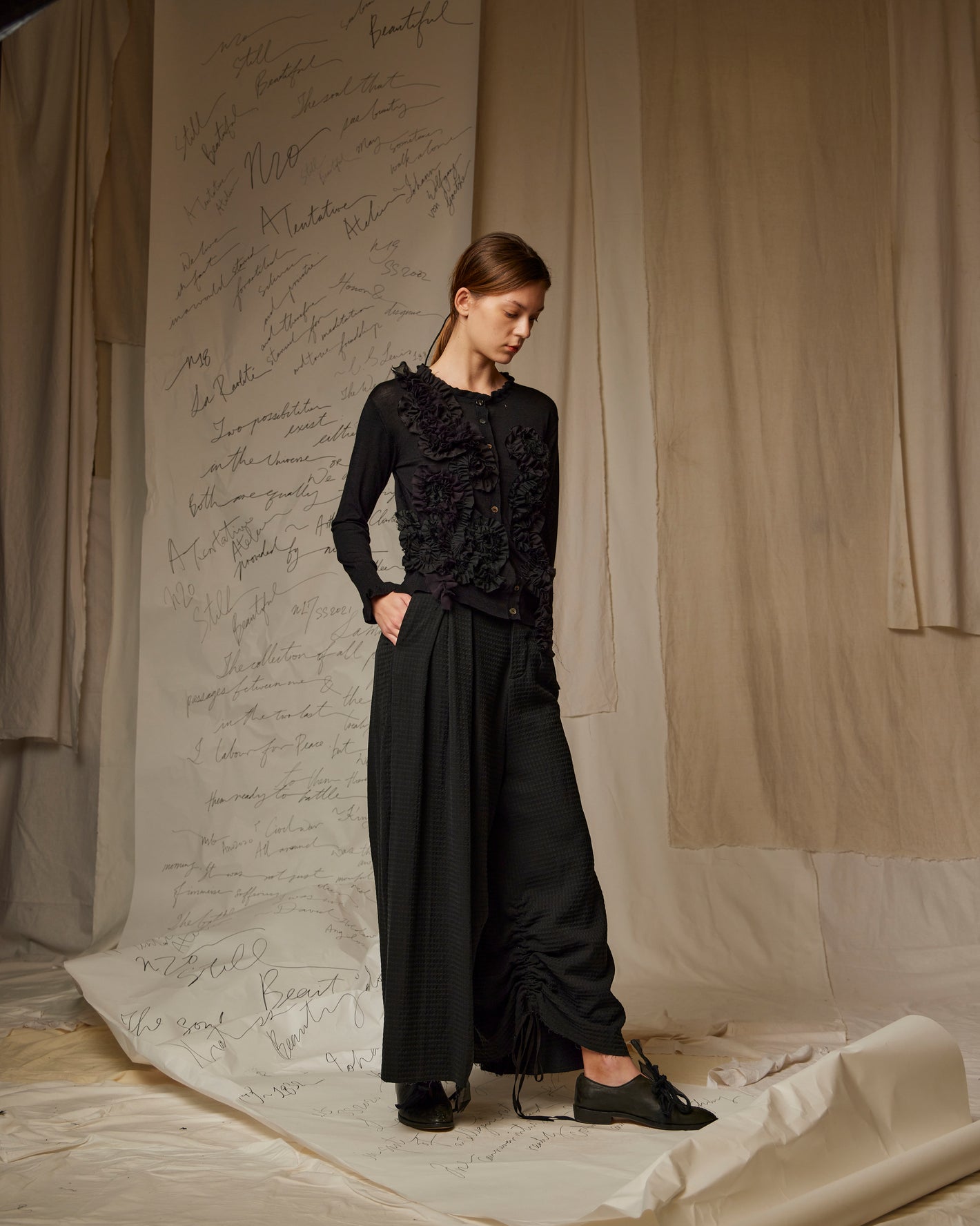 A Tentative Atelier SS23 Lookbook Womens black cardigan with ruffle appliqué on the body, and black wide leg trousers