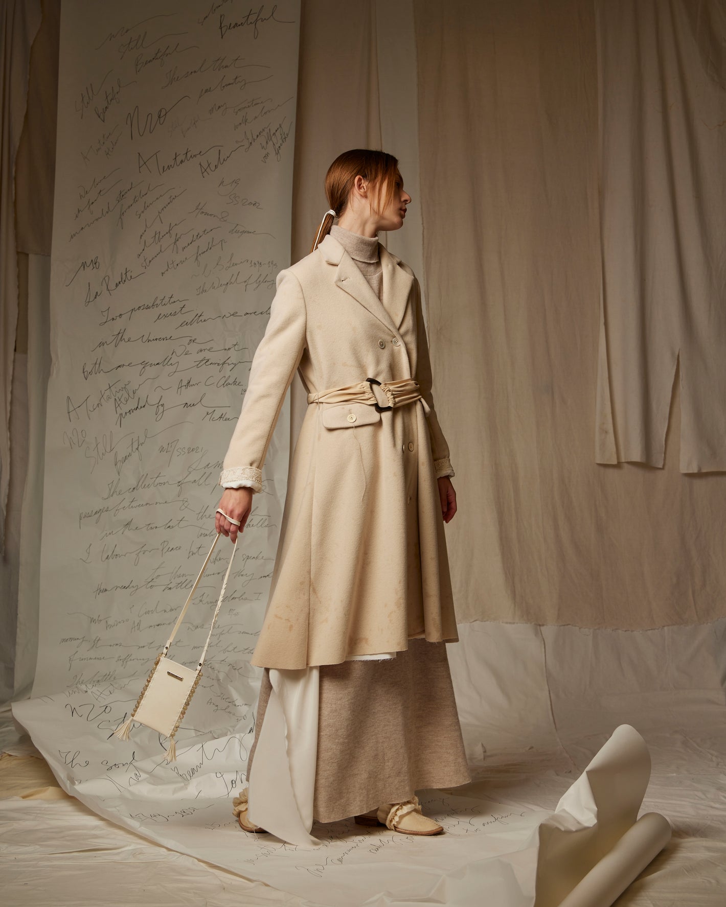 A Tentative Atelier SS23 Lookbook Womens Beige womens belted coat, knit dress and cream strap bag ensemble
