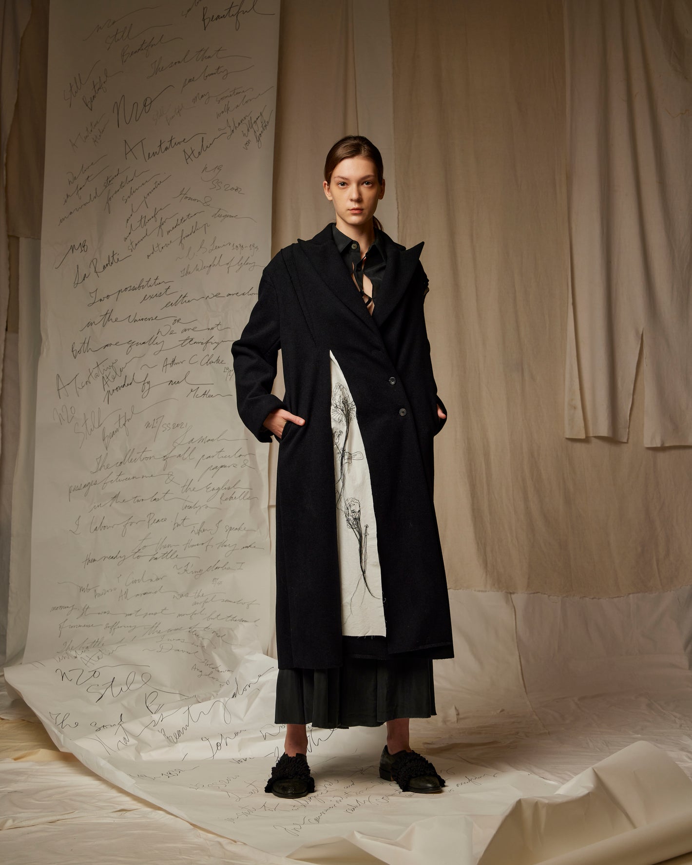 A Tentative Atelier SS23 Lookbook Womens black coat featuring a contrasting white embroidered panel