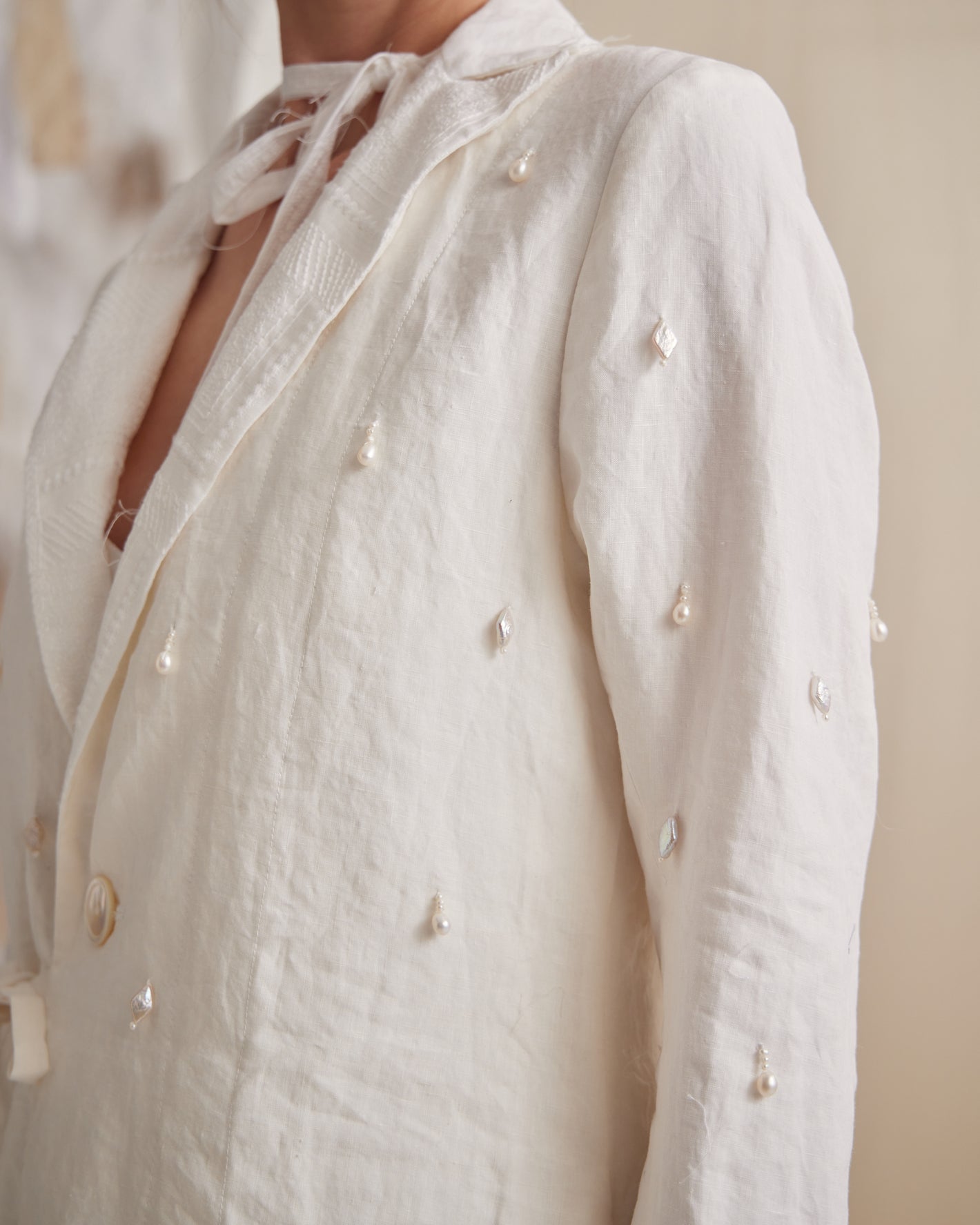 A Tentative Atelier SS23 Lookbook crop of a Womens white coat embellished with pearl and bead pendants