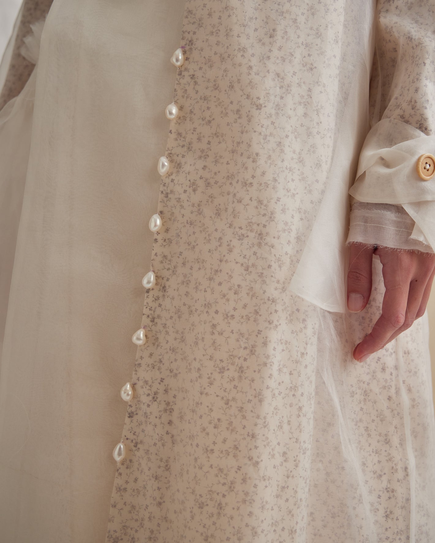 A Tentative Atelier SS23 Lookbook Womens crop of a coat, showing a vertical row of ornamental pearl pendants