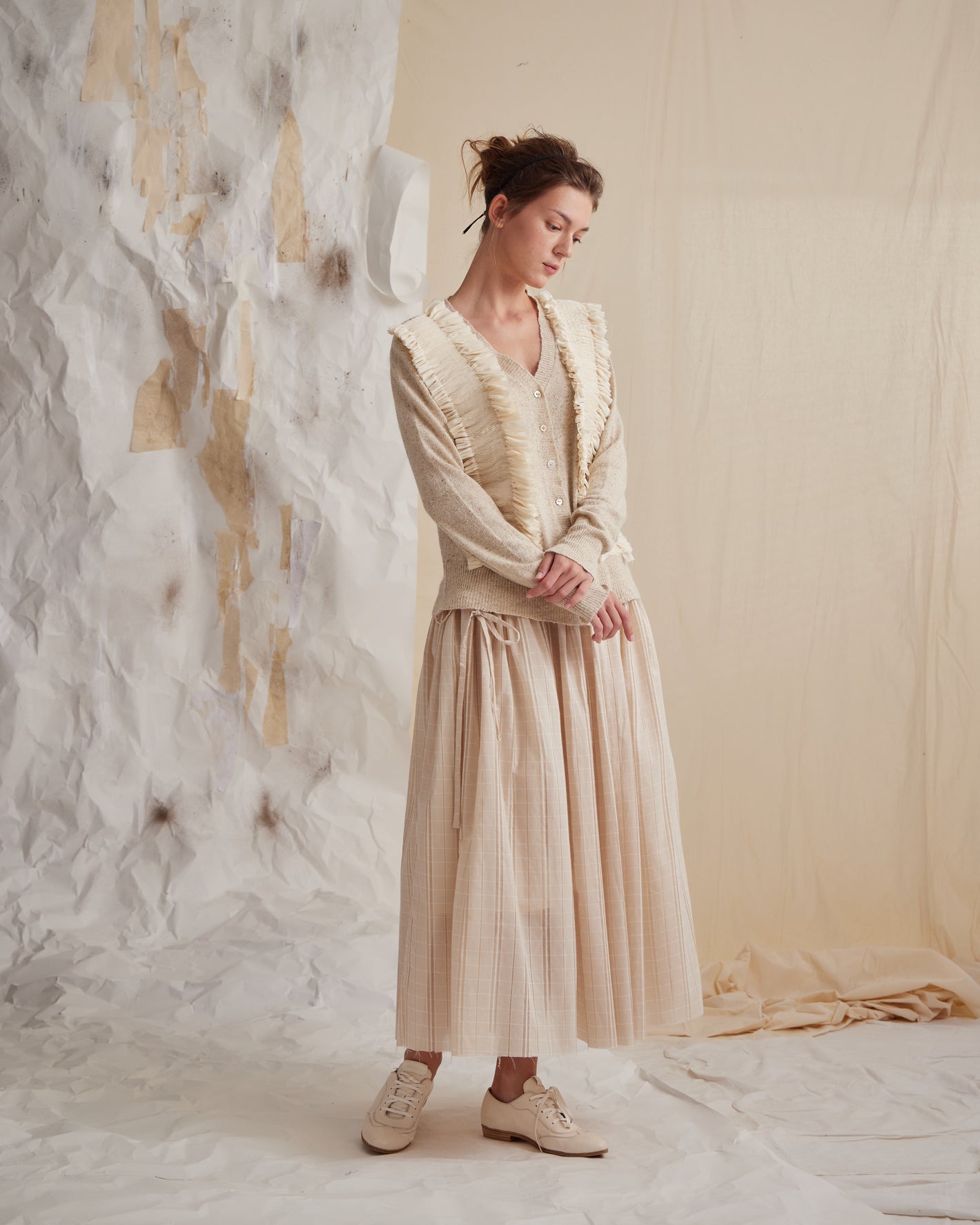 A Tentative Atelier SS23 Lookbook Womens beige cardigan featuring smocked front appliqué panels and wide leg striped beige trousers