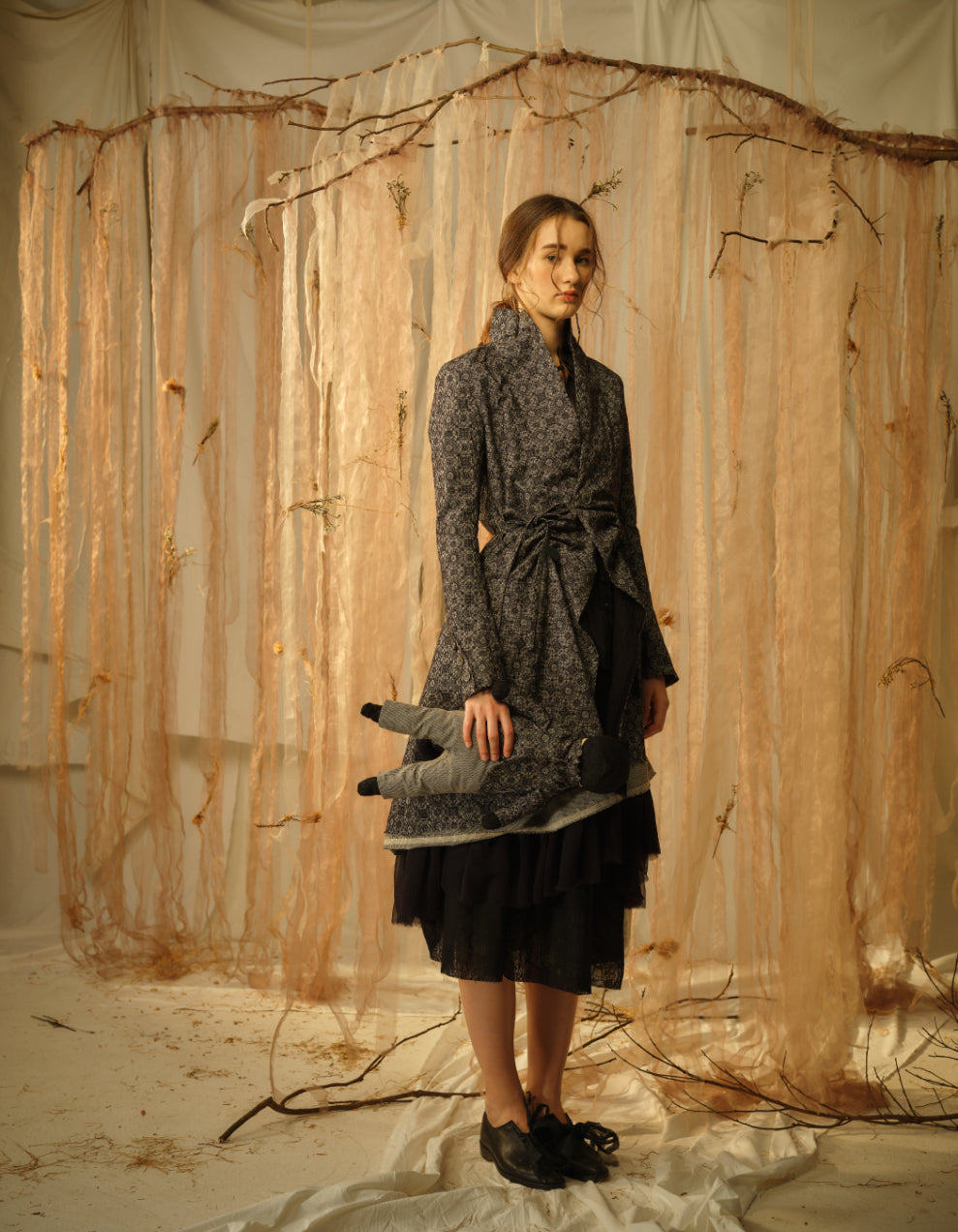 A Tentative Atelier SS21 Lookbook Womens grey patterned high collar belted coat and matching toy plushie