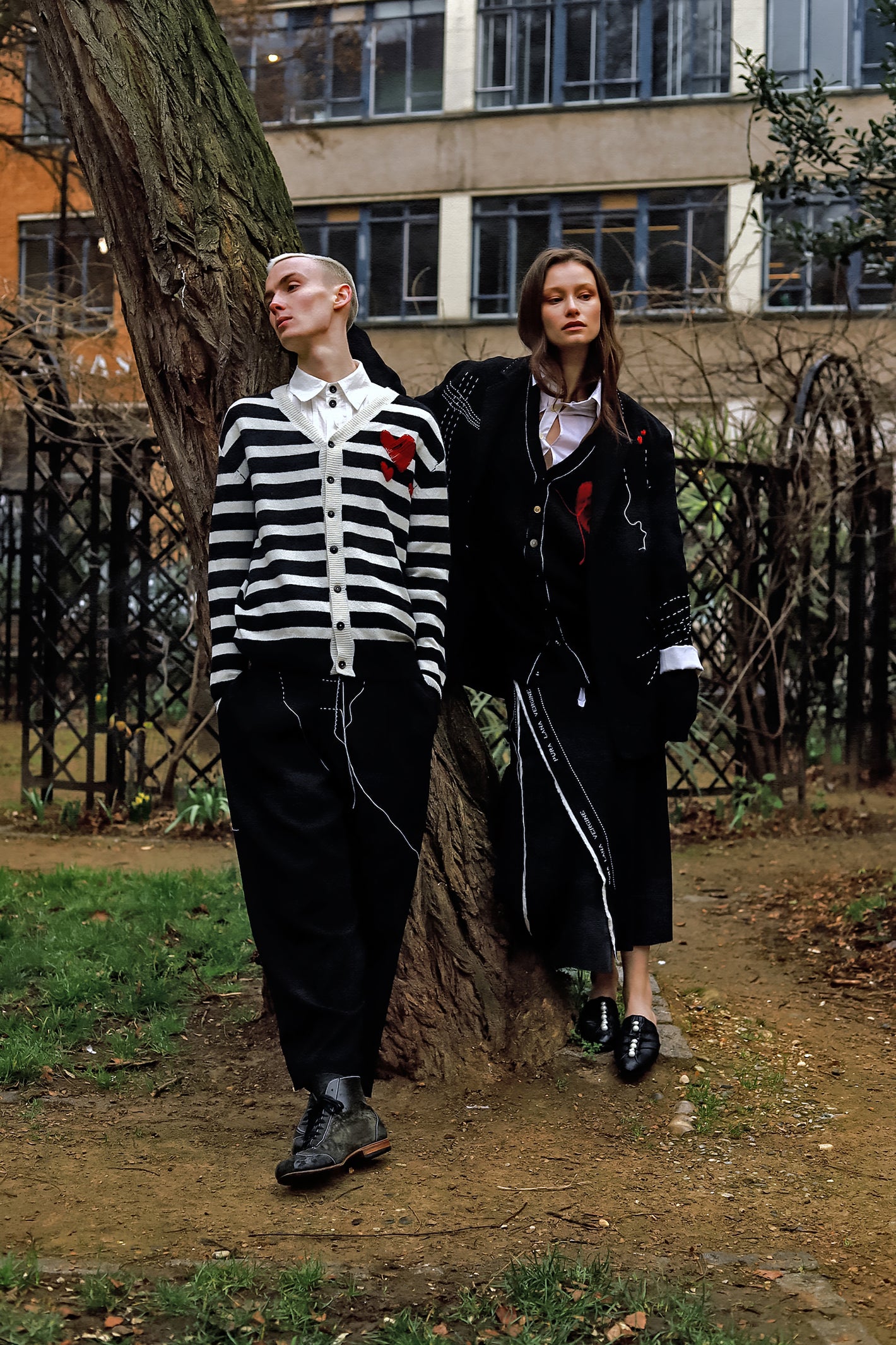 A Tentative Atelier AW23 Lookbook Mens monochrome striped cardigan with heart chest patch and Womens long black coat