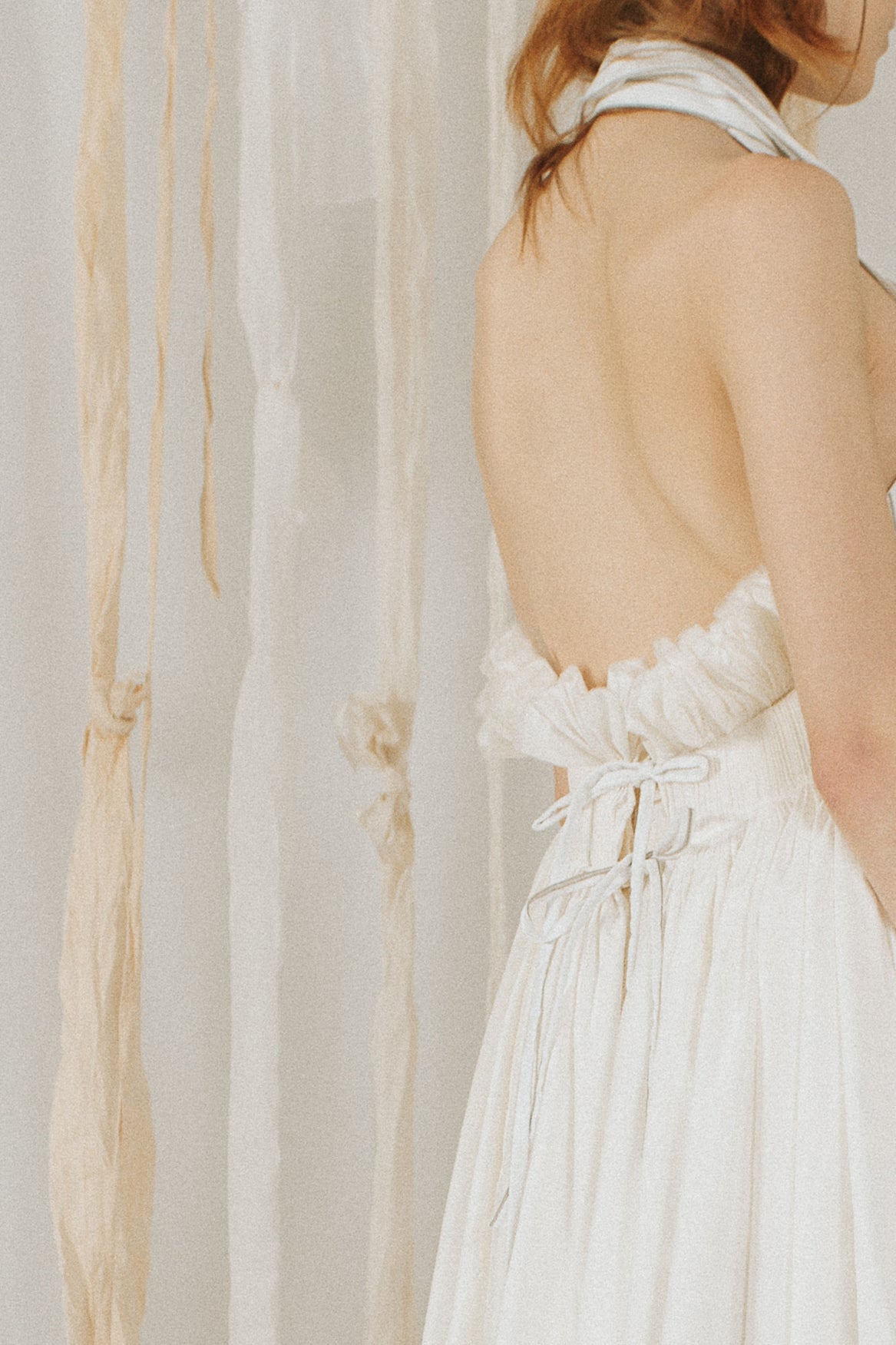 A Tentative Atelier SS18 Lookbook Womens crop of a white halter dress showing the ribbon ties on the back and ruffle trim