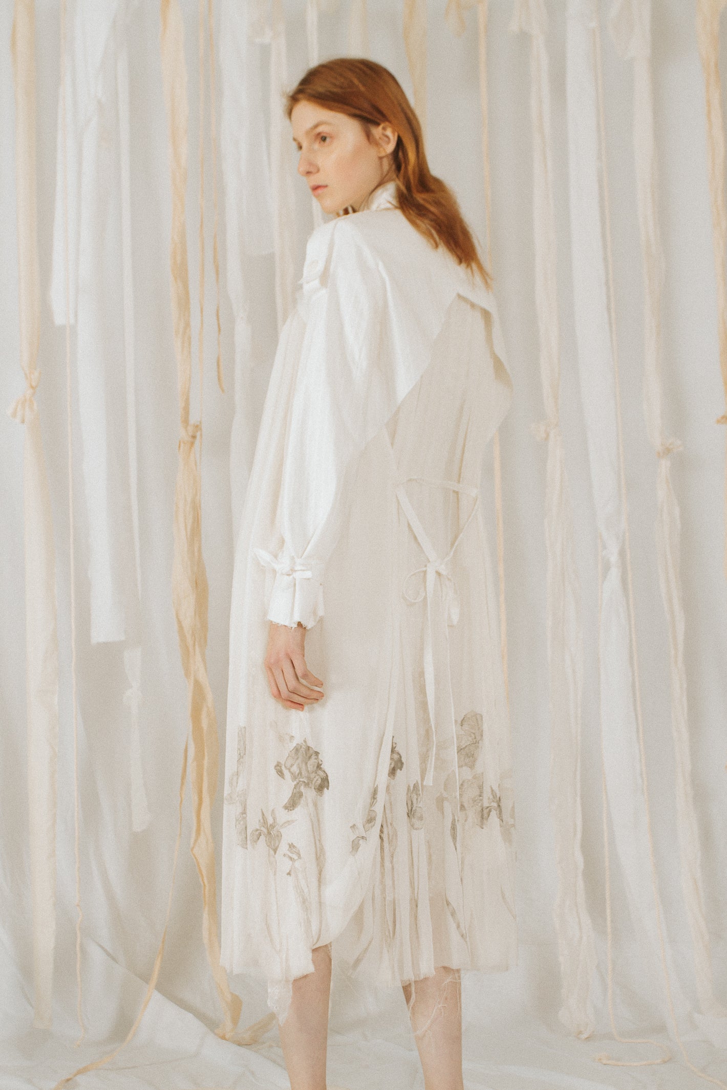A Tentative Atelier SS18 Lookbook Womens back of a white dress shirt dress with printed hem and ribbon tie cuffs