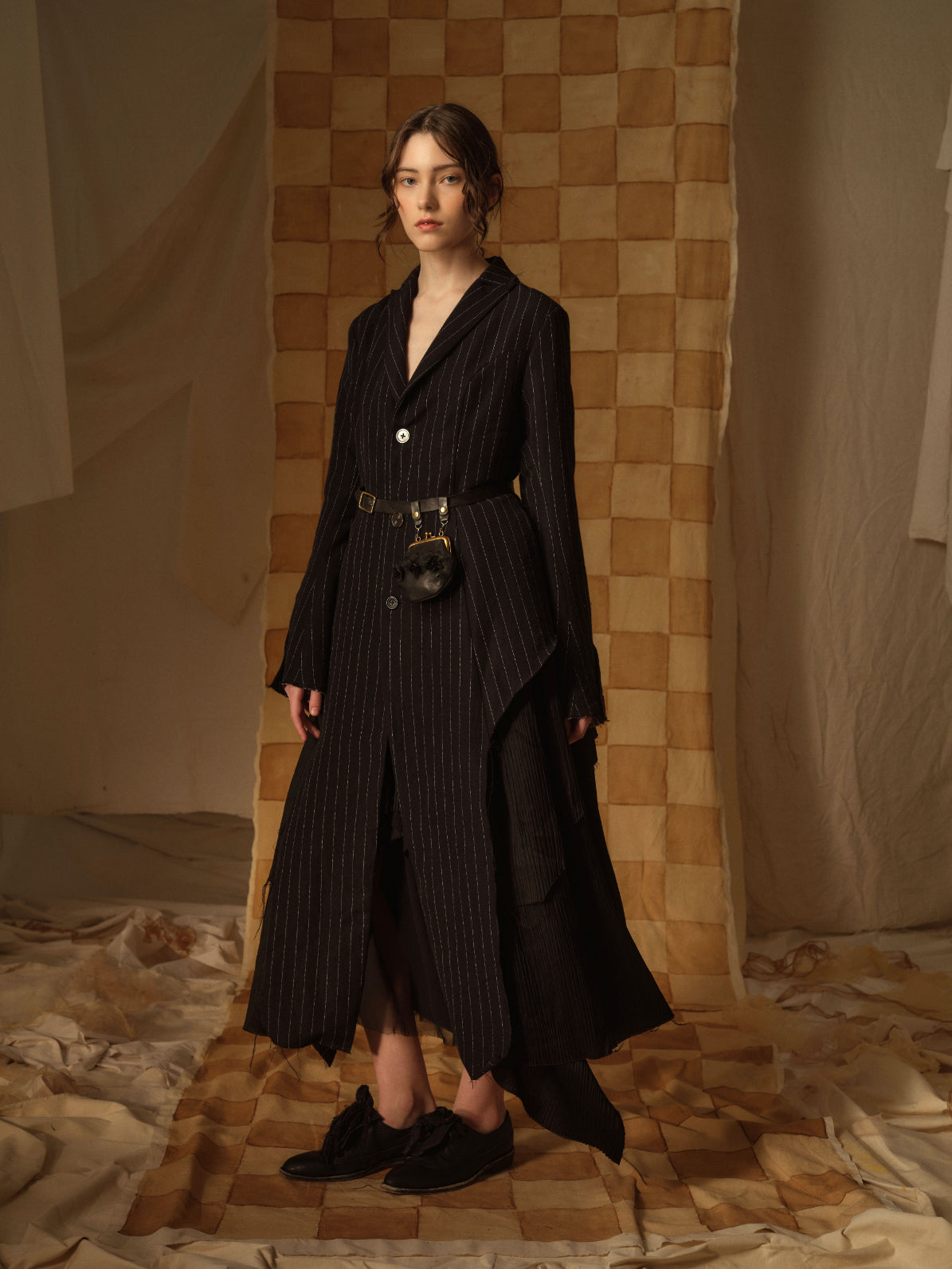 A Tentative Atelier AW21 Lookbook Womens black striped coat accessorised with a black belt and purse