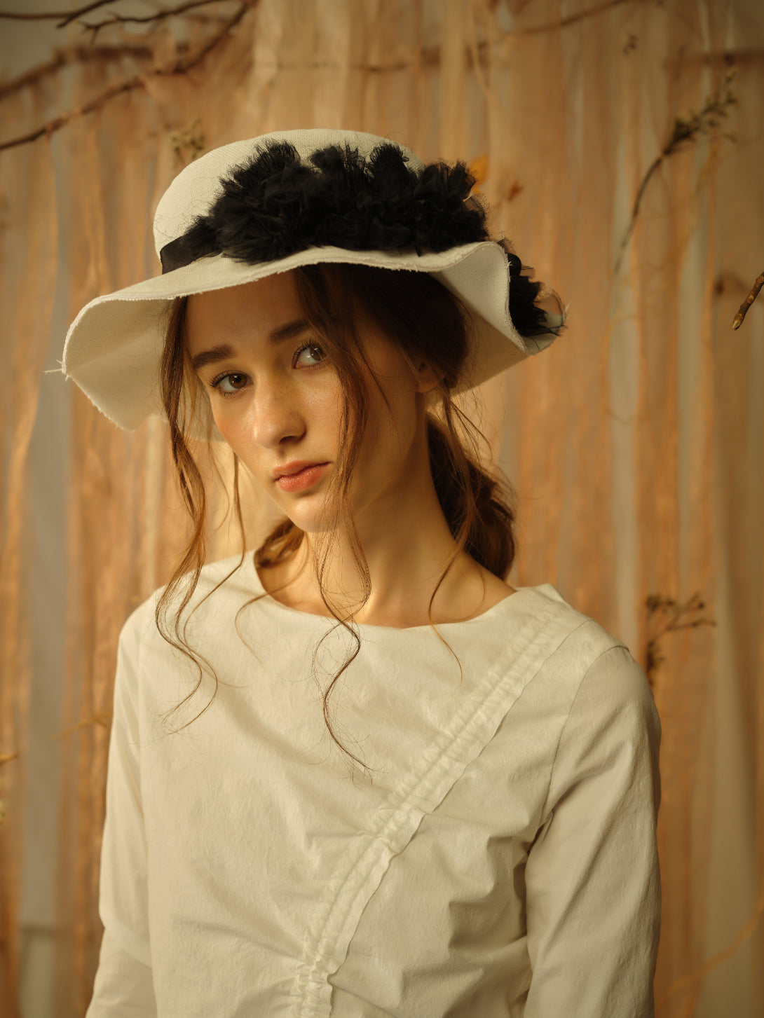 A Tentative Atelier SS21 Lookbook Womens crop of a white hat with a black ribbon band and floral tulle appliqué