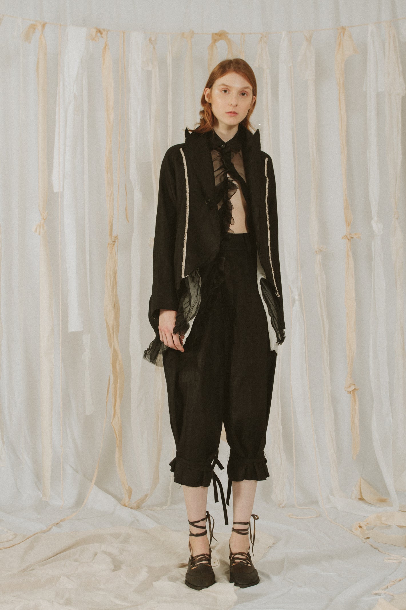 A Tentative Atelier SS18 Lookbook Womens black peak lapel jacket and black cuffed knee length trousers
