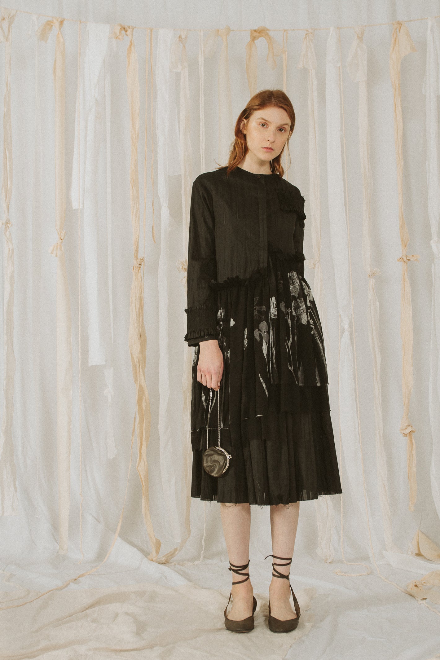 A Tentative Atelier SS18 Lookbook Womens black round neck shirt dress with printed black cloth appliqué at the waist, styled with a mini black leather chain purse