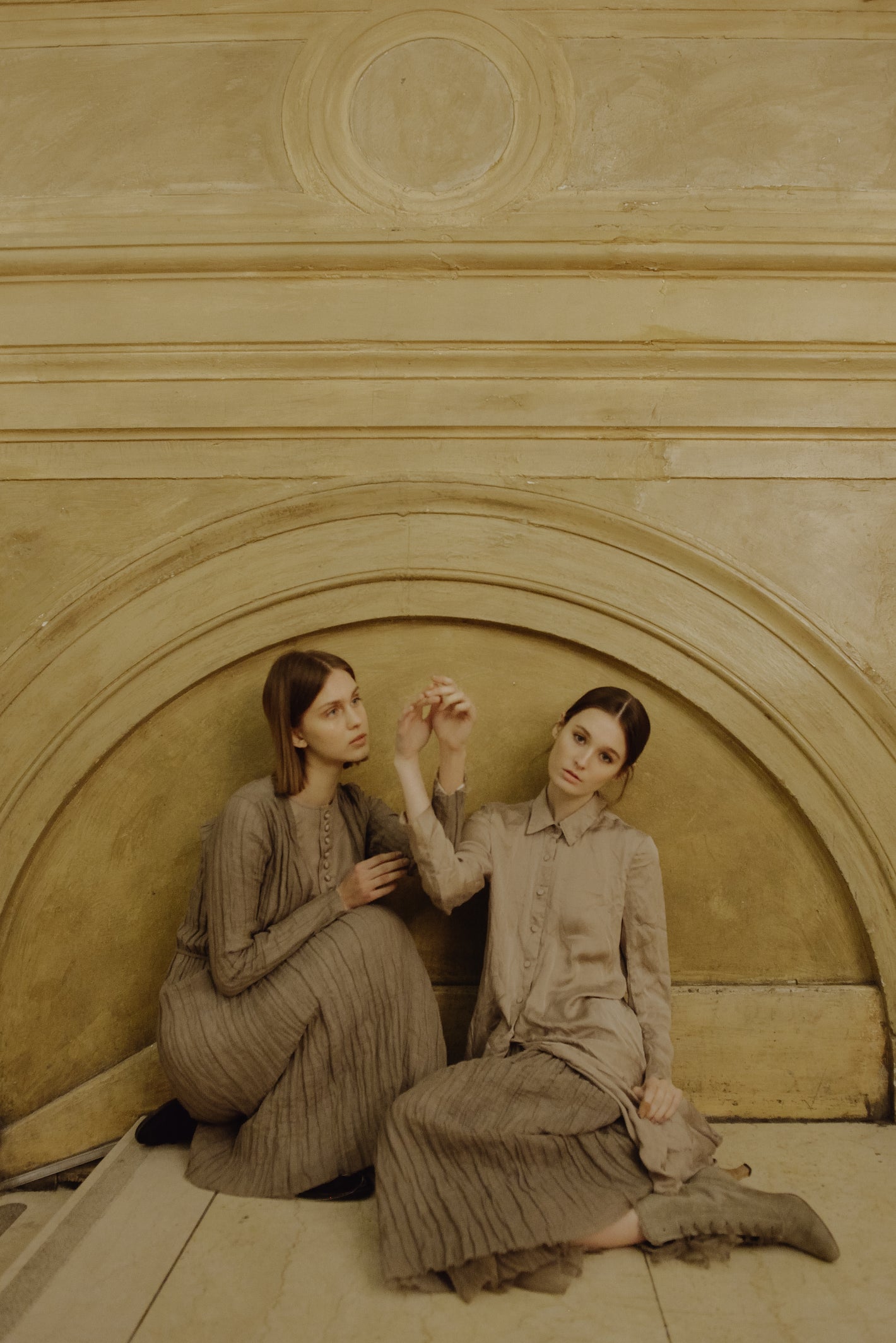 A Tentative Atelier AW19 Lookbook Womens two models, wearing a pleated brown dress, and beige button up shirt with a pleated skirt