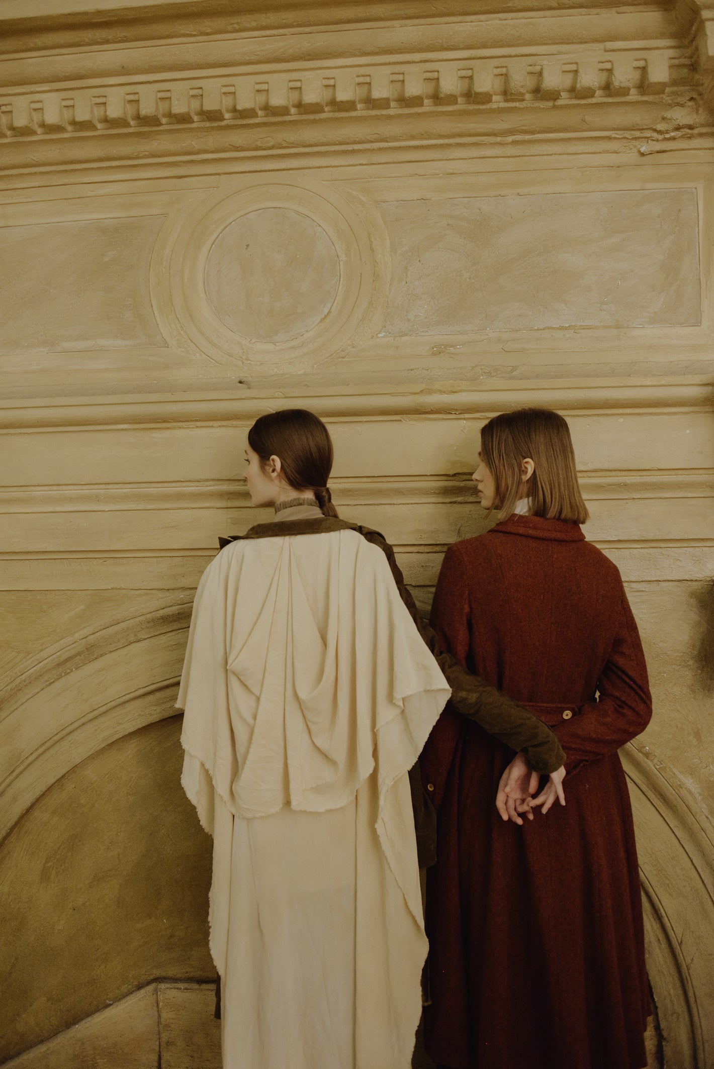 A Tentative Atelier AW19 Lookbook Womens crop of two models pictured from behind wearing a white draped coat and red coat respectively