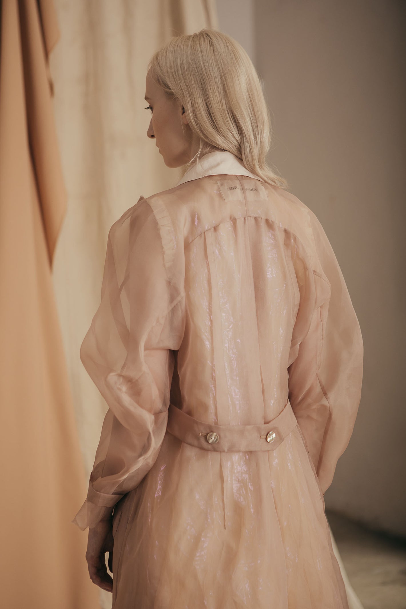 A Tentative Atelier SS20 Lookbook Womens crop of nude and white semi sheer coat from behind, showing the belted back