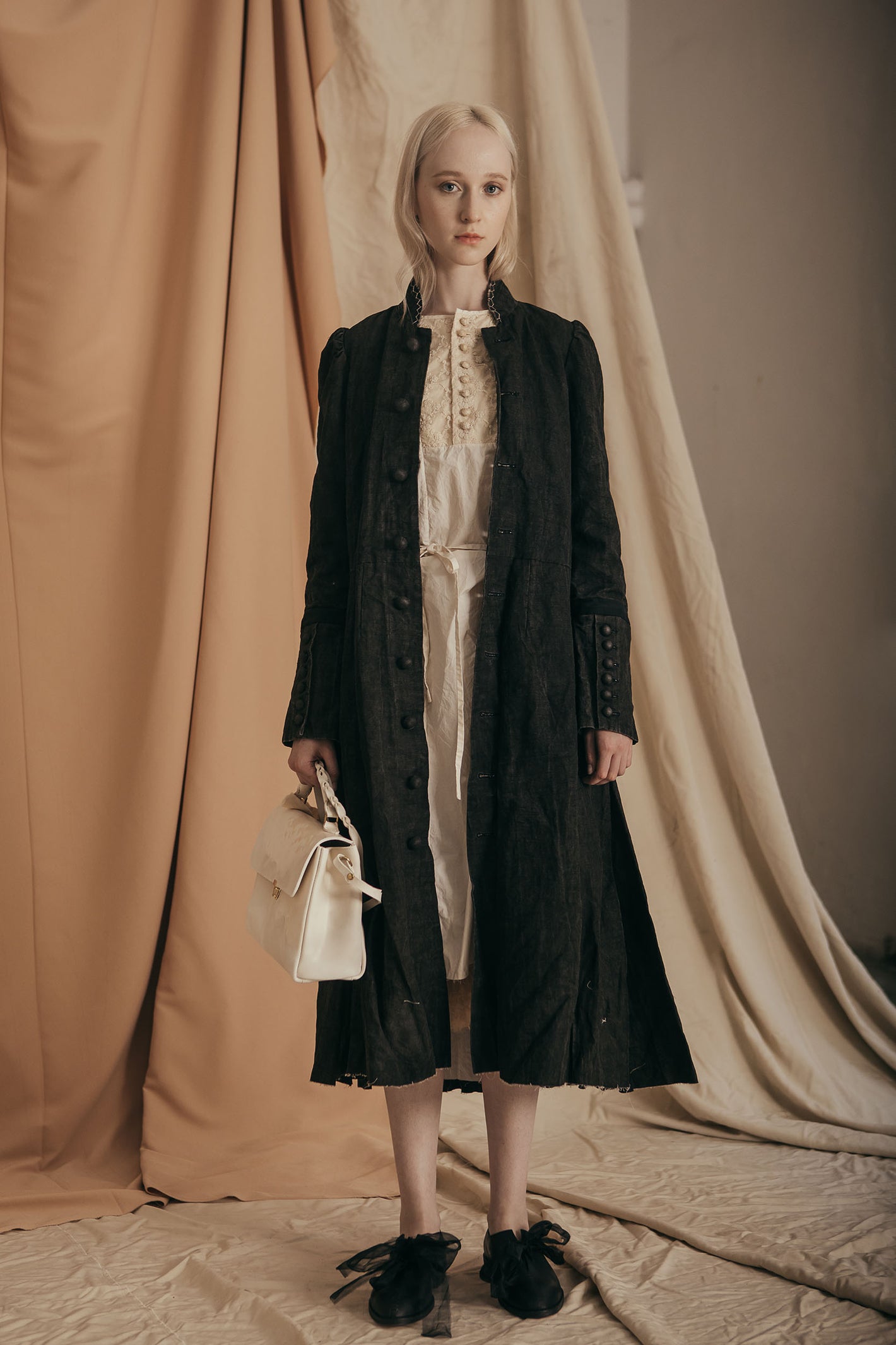 A Tentative Atelier SS20 Lookbook Womens black coat and white leather top handle bag