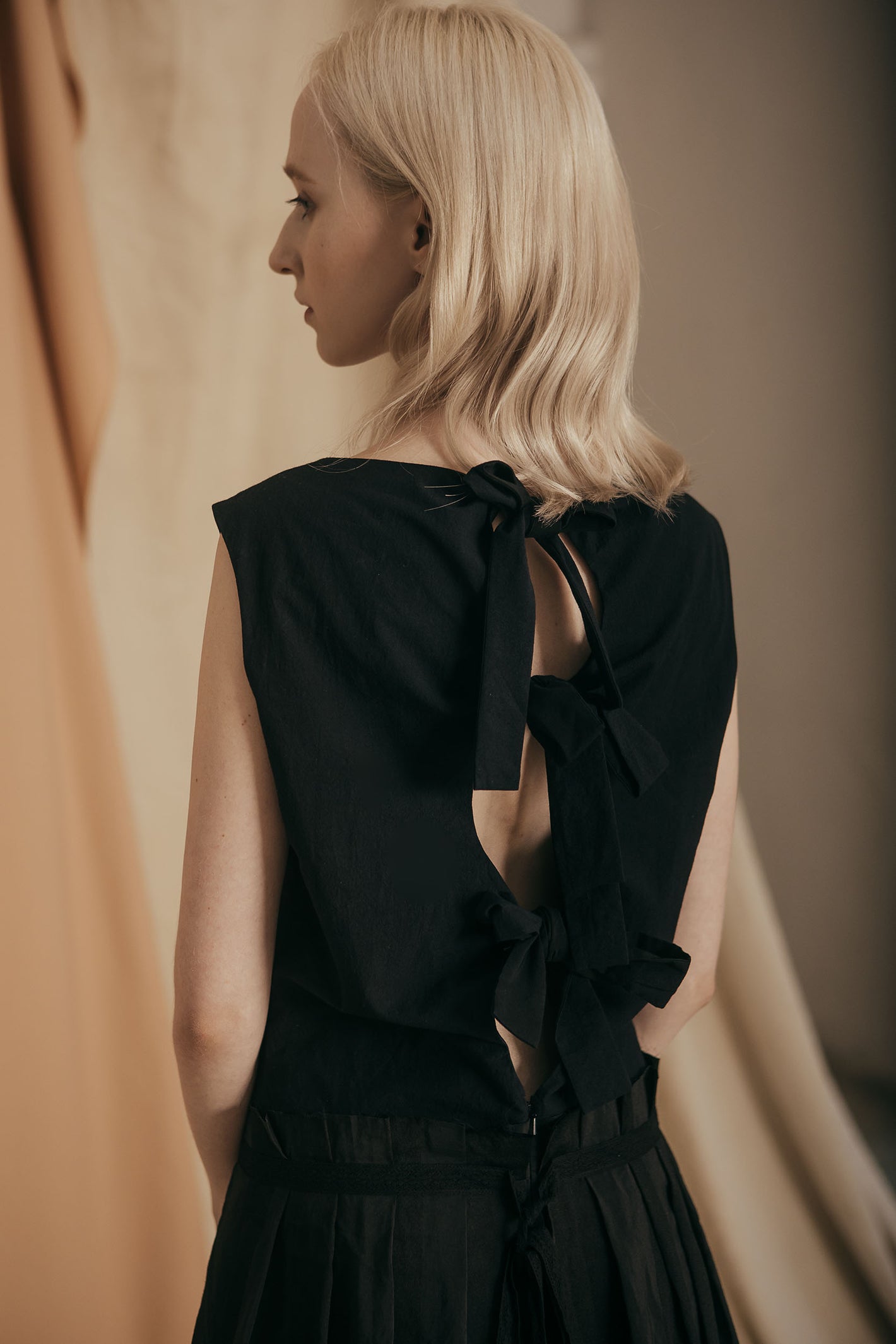 A Tentative Atelier SS20 Lookbook Womens crop of the back of a black top, showing keyhole with ribbon tie fastenings