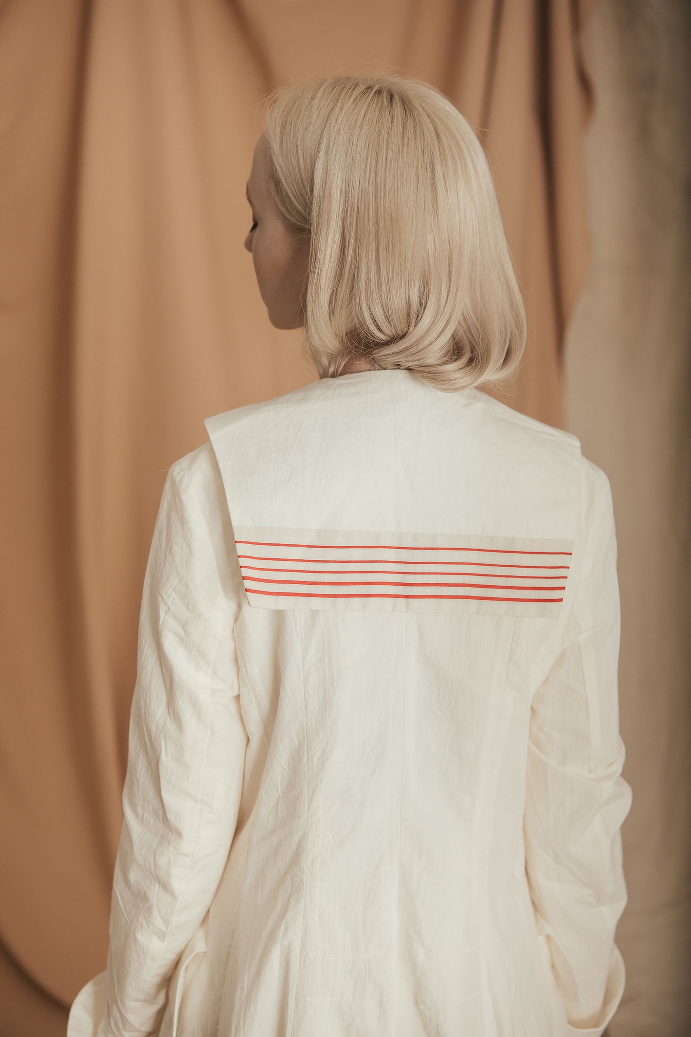 A Tentative Atelier SS20 Lookbook Womens crop of the back of a white coat, featuring a sailors shirt yoke with red stripes