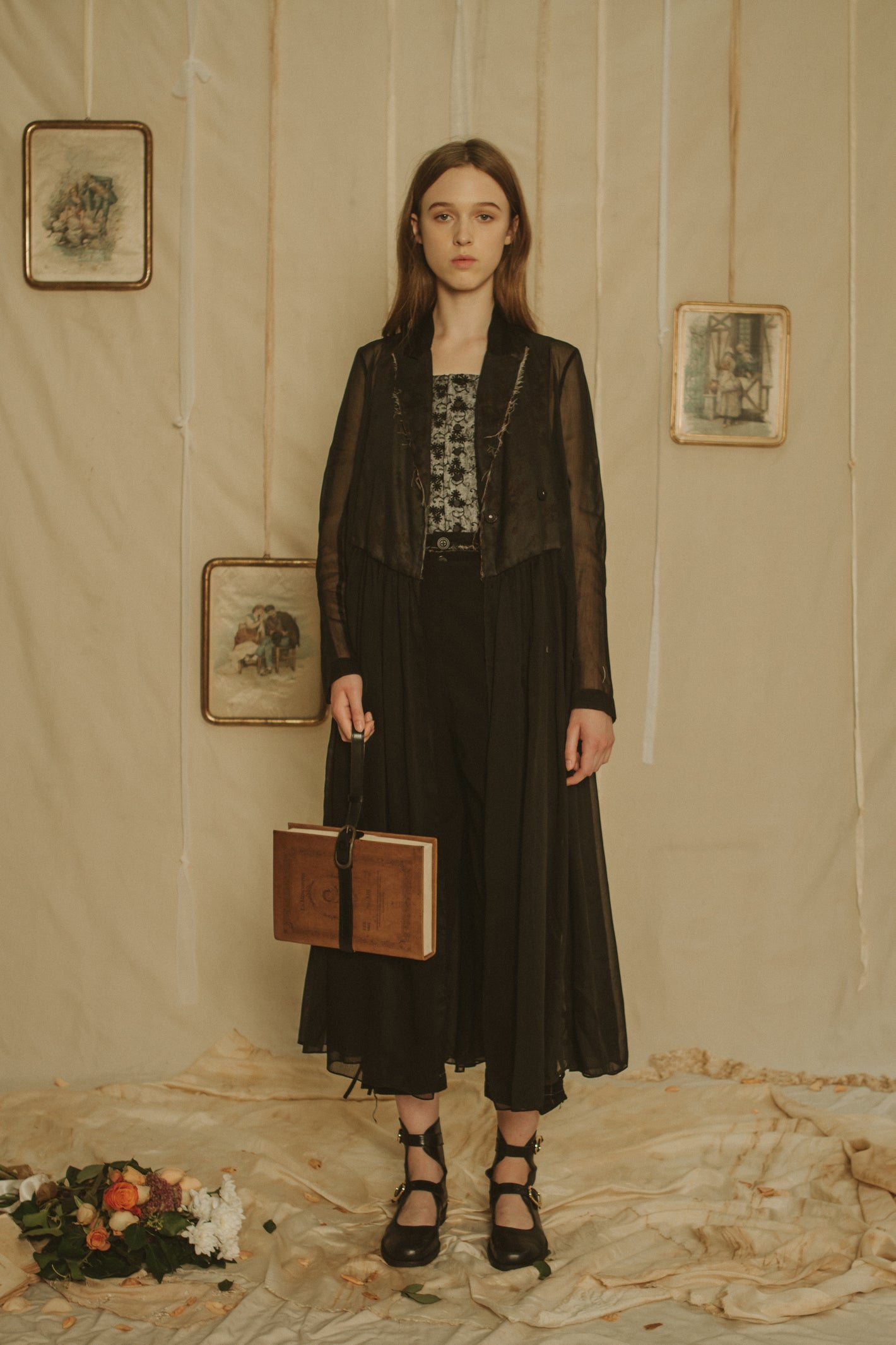 A Tentative Atelier SS19 Lookbook Womens black coat with sheer sleeves and pleated skirt, and "Book" clutch