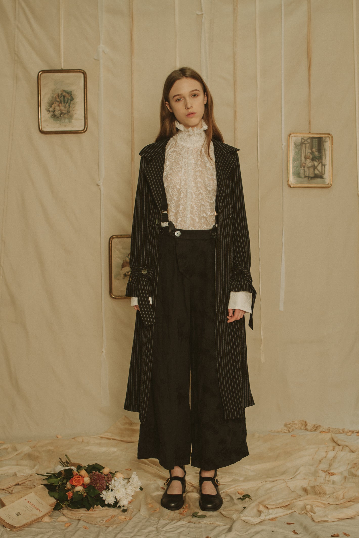 A Tentative Atelier SS19 Lookbook Womens black striped coat, black suspender trousers, and white lace blouse